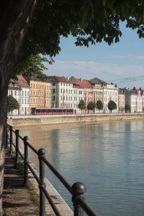 Red Tram Along a European Riverfront